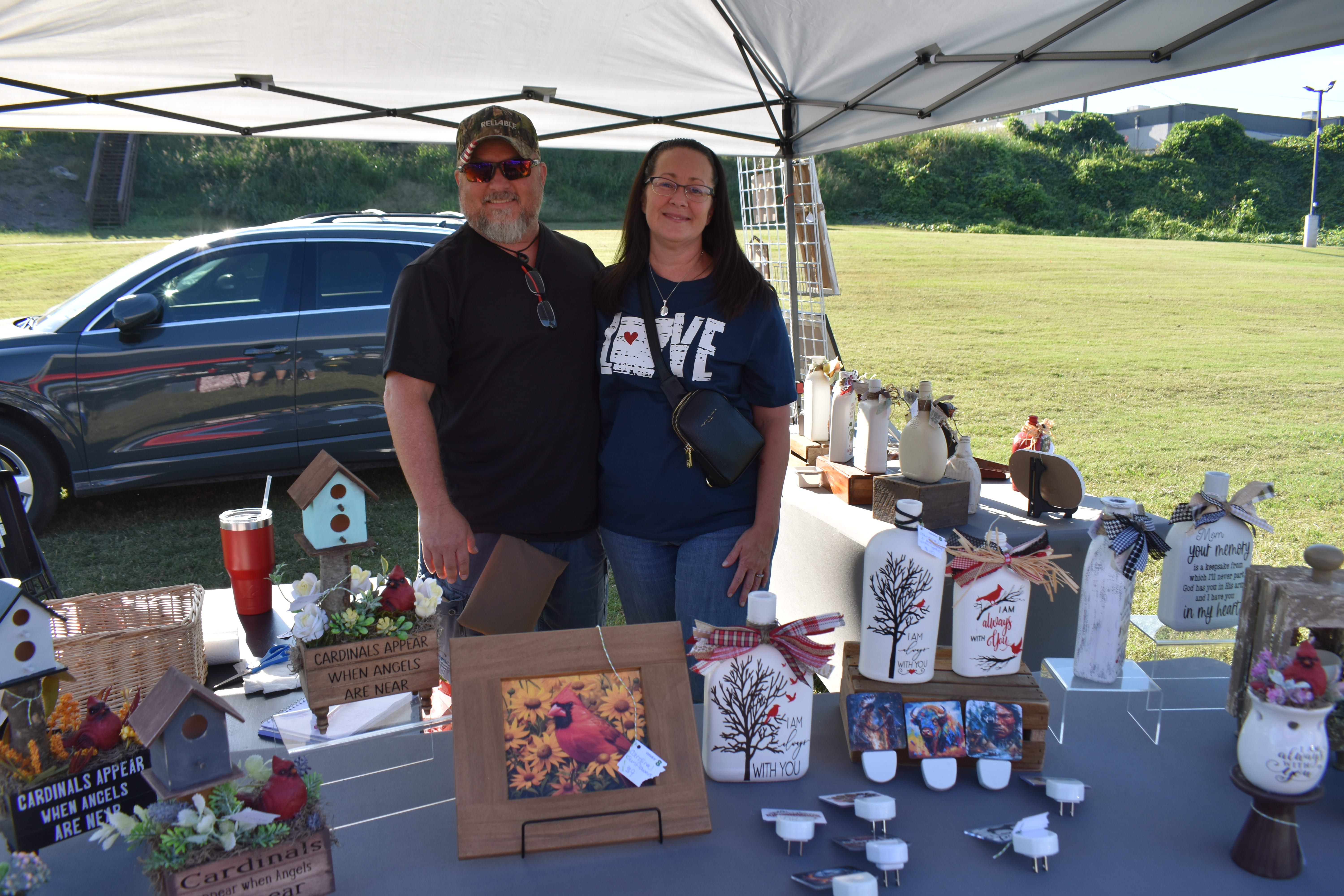 Couple at a cardinal-themed home décor vendor booth at October Festival 2025