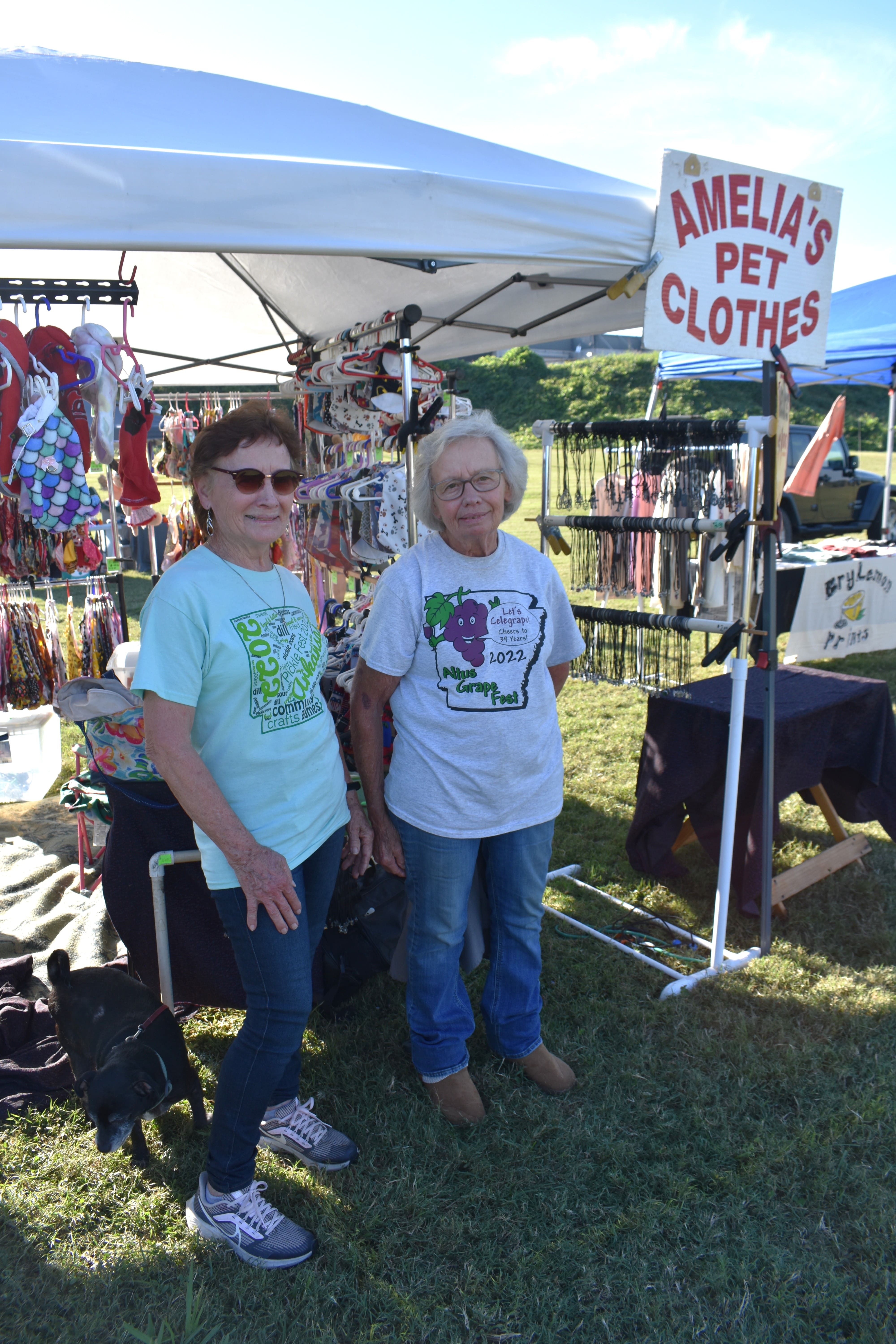 Two women standing in front of Amelia's Pet Clothes vendor booth at October Festival 2025