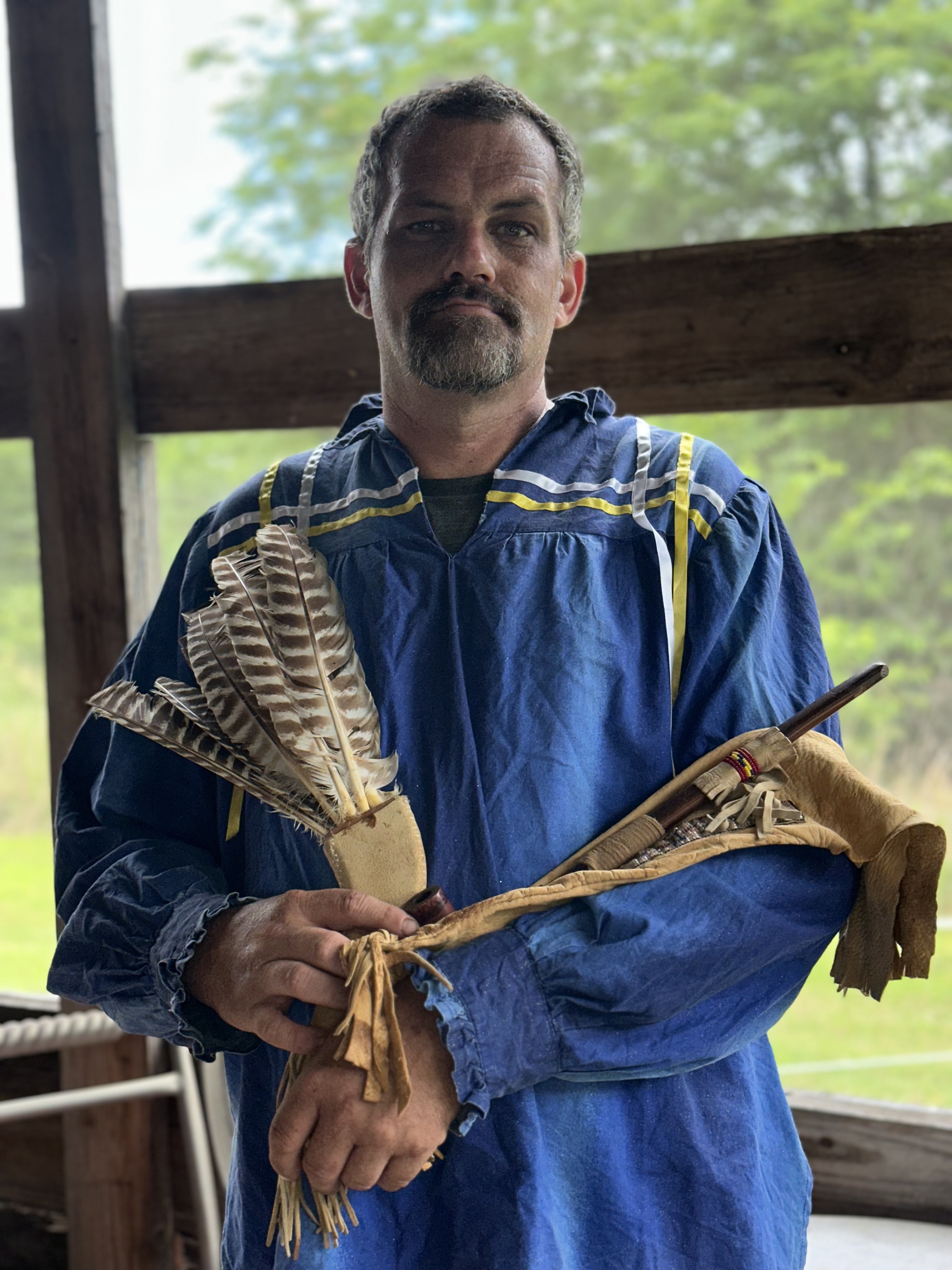 Tribal member in Cherokee ribbon shirt holding sacred feathers at Green Corn Ceremony 2026