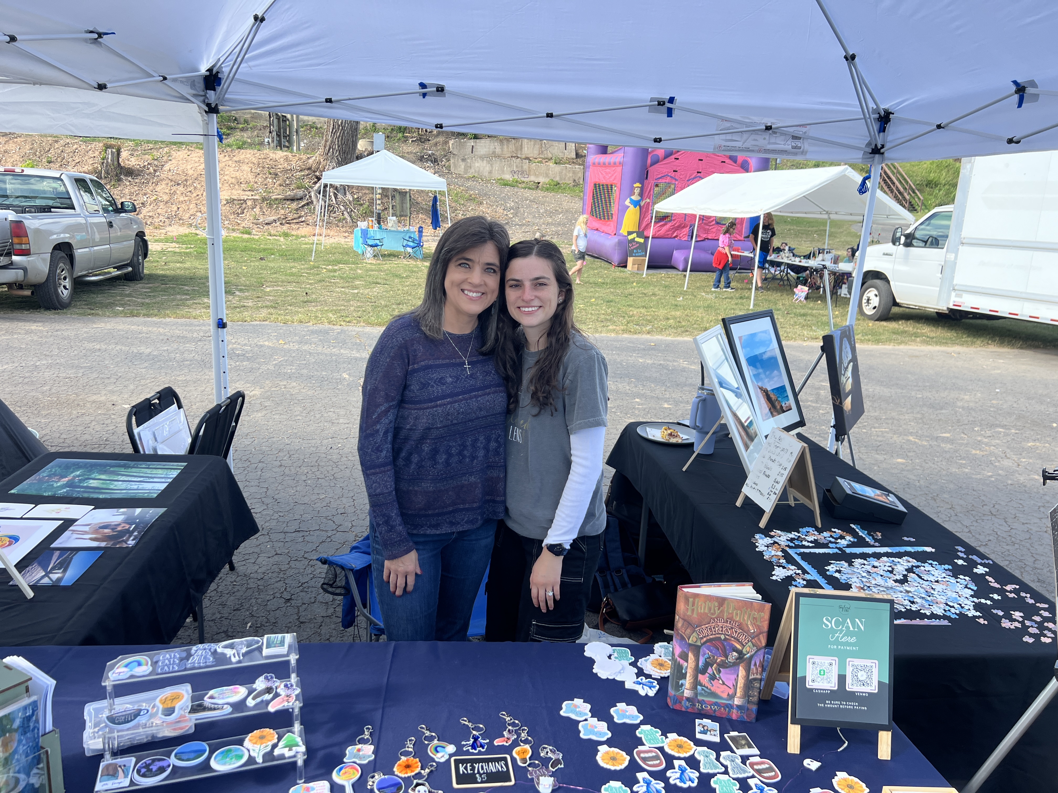Two women smiling at their vendor booth at October Festival 2025